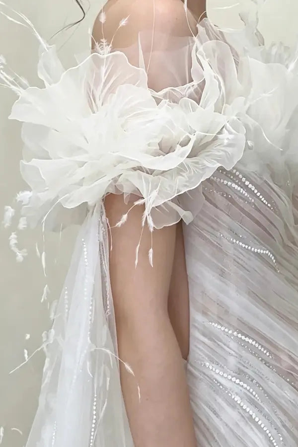 Détail spectaculaire des manches à volants en tulle et plumes légères pour un look de mariée couture unique.