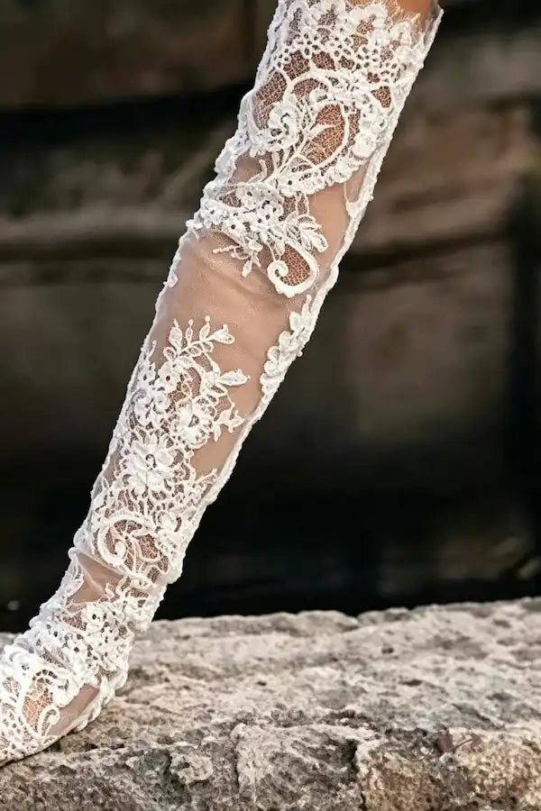 Détail de la dentelle fine sur les manches amovibles de mariée, montrant l'effet seconde peau et la finesse des motifs floraux.