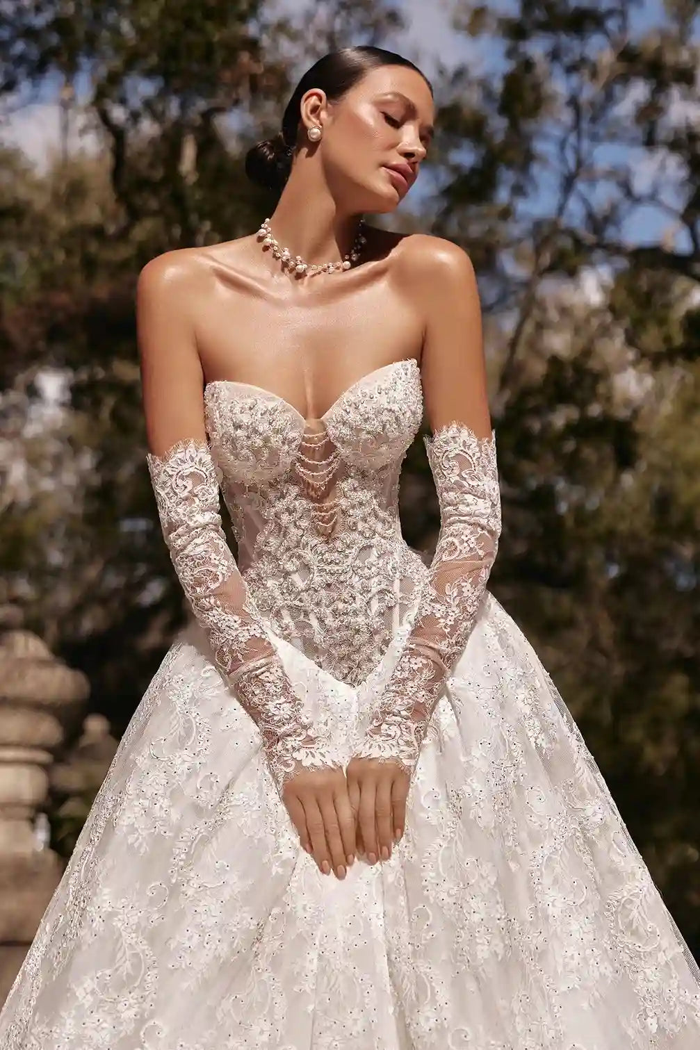 Élégance haute couture pour cette mariée avec des manches amovibles en dentelle souple qui épousent le bras comme un gant romantique.
