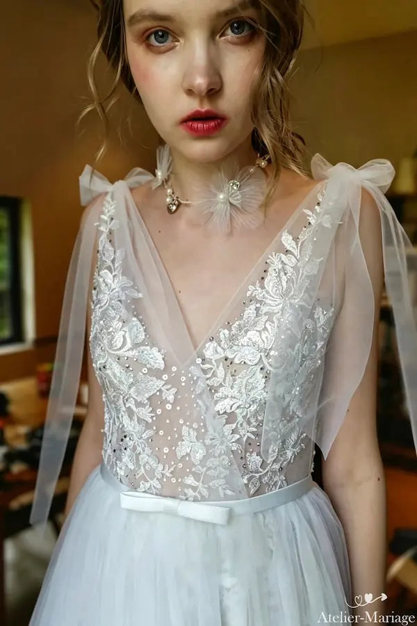 Zoom sur les manches cape en tulle vaporeux pour un effet aérien et romantique.