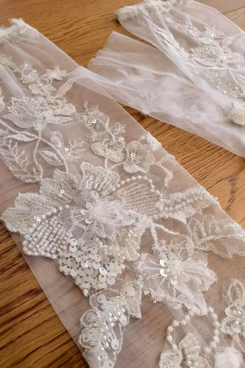 Vue détaillée de la transparence du tulle et des finitions artisanales des manches longues pour une robe de mariée 2-en-1.