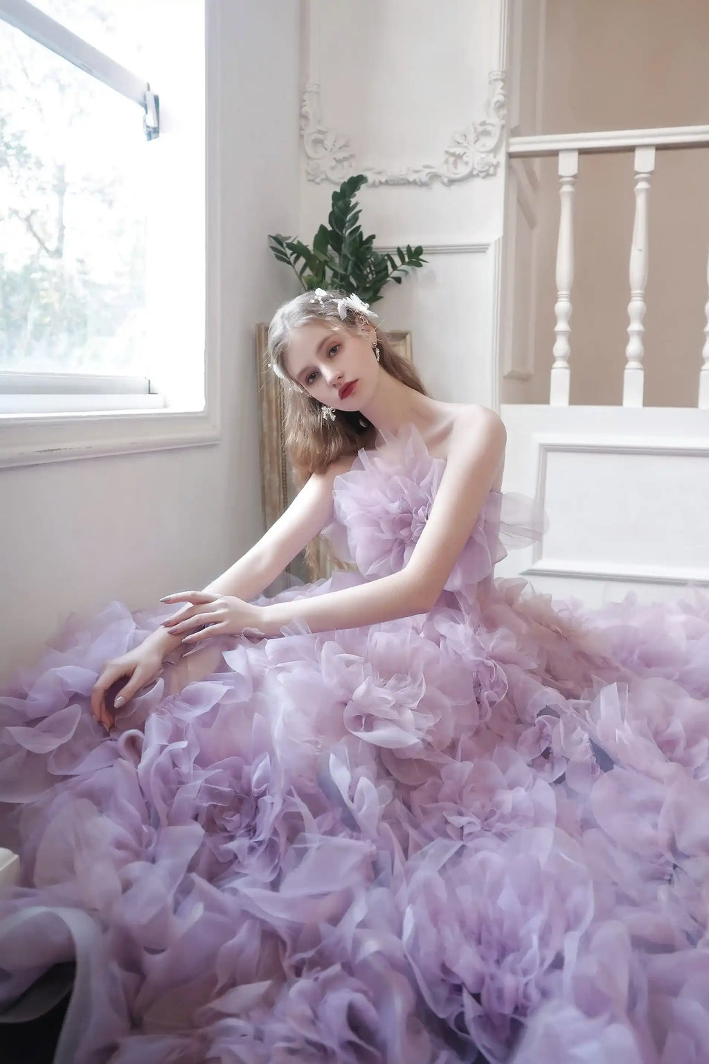 Mariée assise au milieu de sa robe en tulle lilas, créant une ambiance de conte de fées romantique.