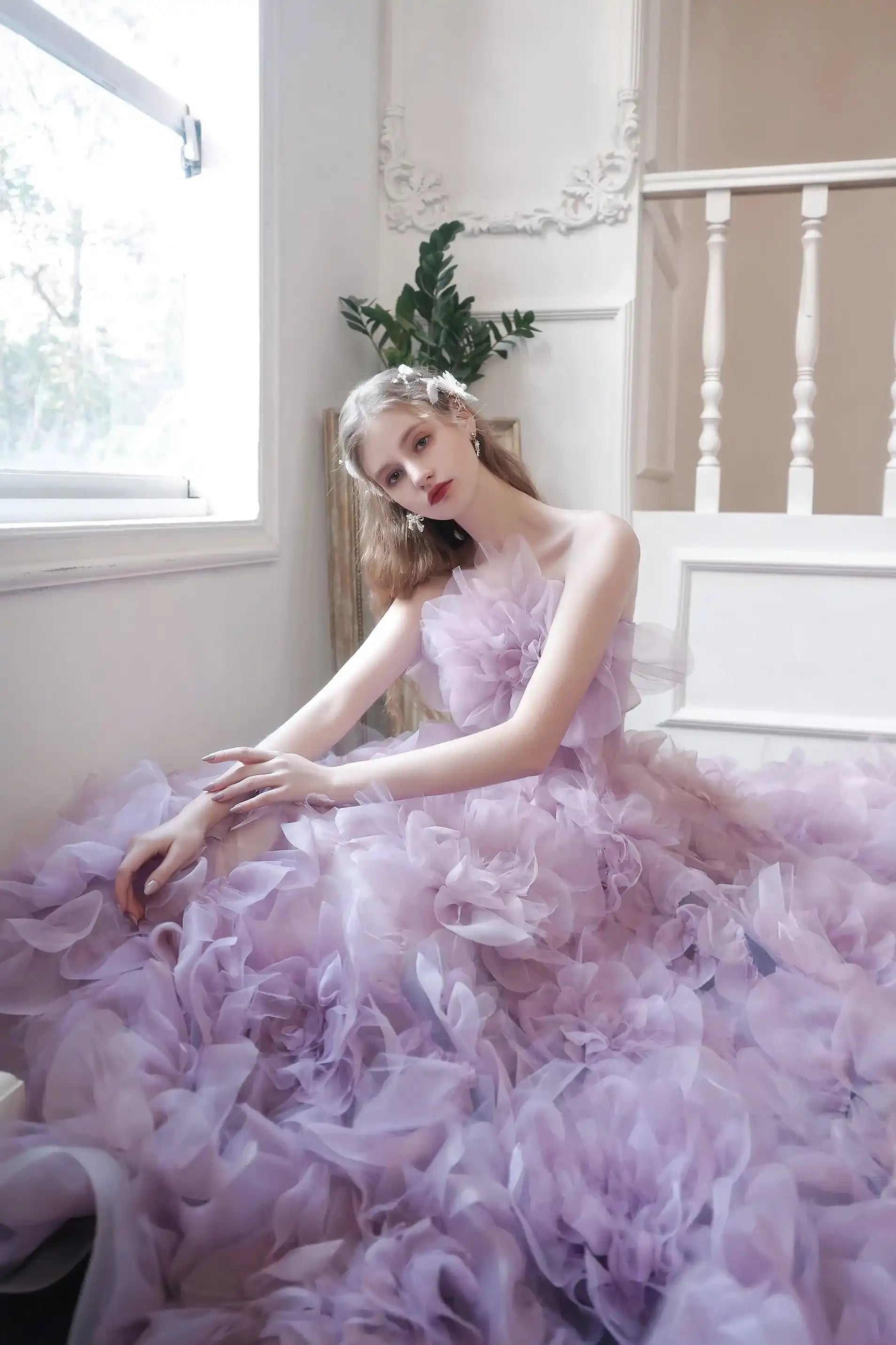 Mariée assise au milieu de sa robe en tulle lilas, créant une ambiance de conte de fées romantique.