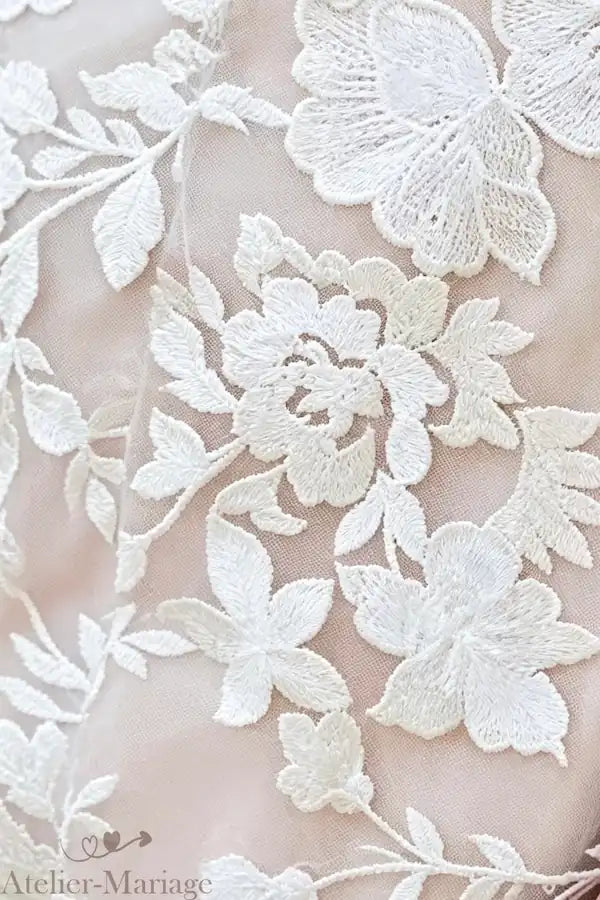 Zoom sur les motifs floraux en dentelle appliqués sur le bustier, mettant en avant la qualité des matières sur-mesure.