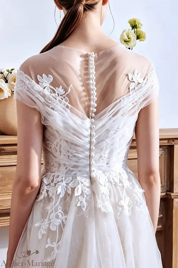 Détail du nœud en tulle sur l'épaule pour un style romantique et aérien.