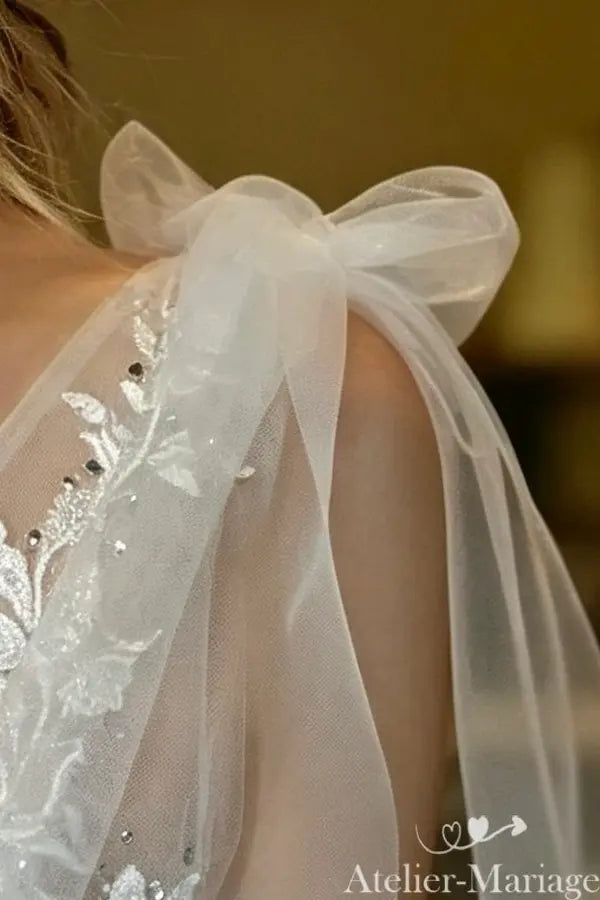 Détail du nœud délicat en tulle sur l'épaule, signature d'un style bohème chic.