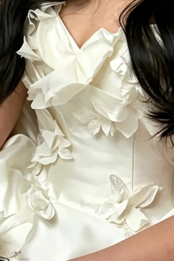 Gros plan sur les papillons 3D sculptés à la main sur le bustier d'une robe de mariée de luxe, créant un relief féerique.