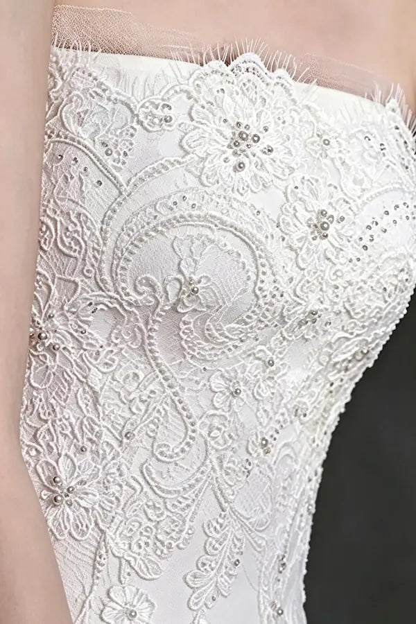Détails de la dentelle perlée et des broderies raffinées sur le bustier d'une robe de mariée princesse.