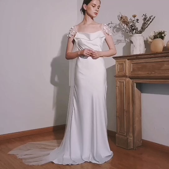 Le mouvement fluide du satin et les détails des manches fleuries 3D.