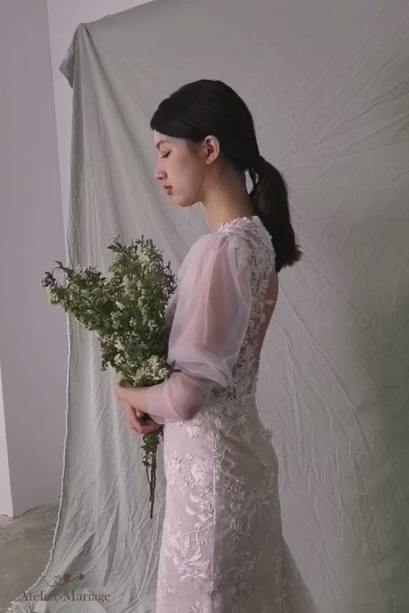 Modèle présentant en vidéo une robe de mariée bohème chic avec de longues manches bouffantes romantiques et transparentes.