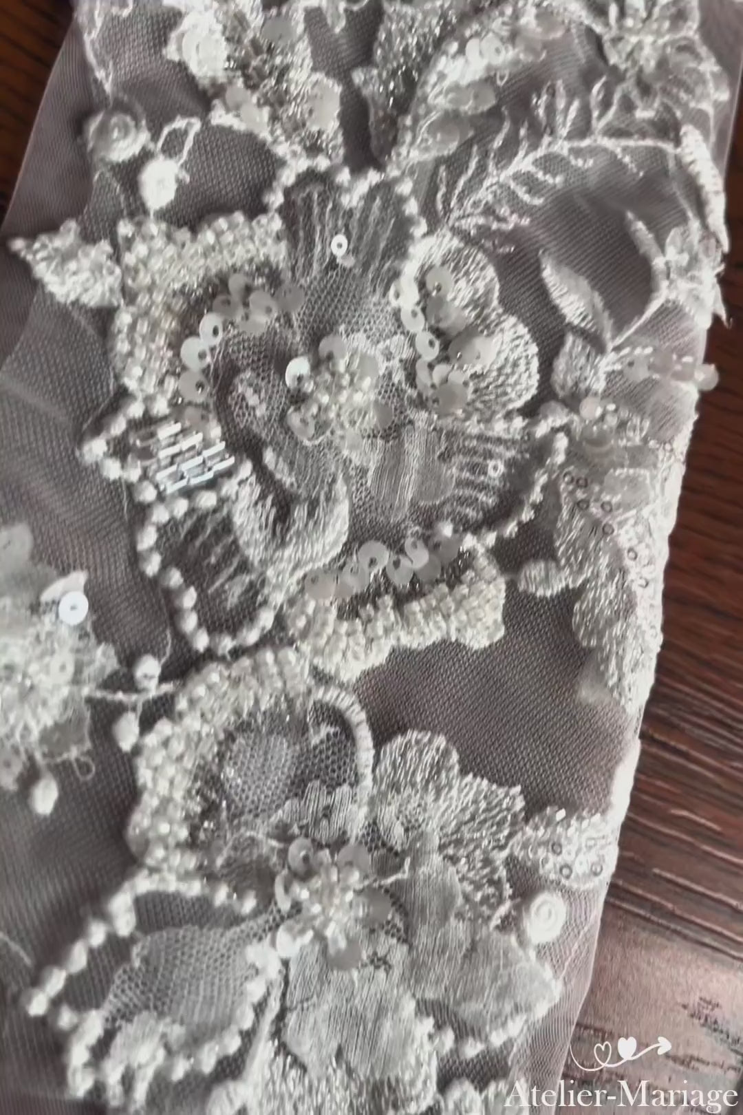 Gros plan vidéo exclusif sur les broderies délicates et les finitions perlées à la main des manches de mariée. Admirez l'artisanat haute couture. Commandez vos manches artisanales.