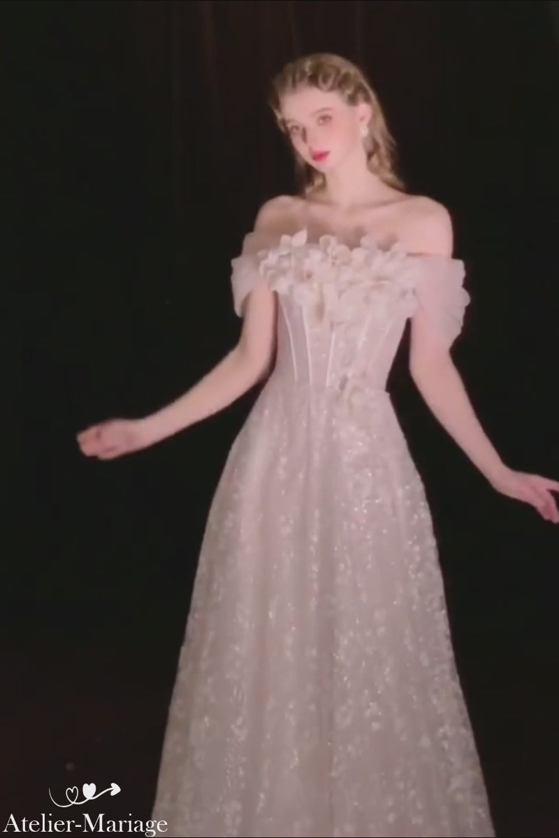 Présentation en studio sur fond noir d'une robe de mariée coupe princesse avec détails scintillants de paillettes et fleurs 3D.