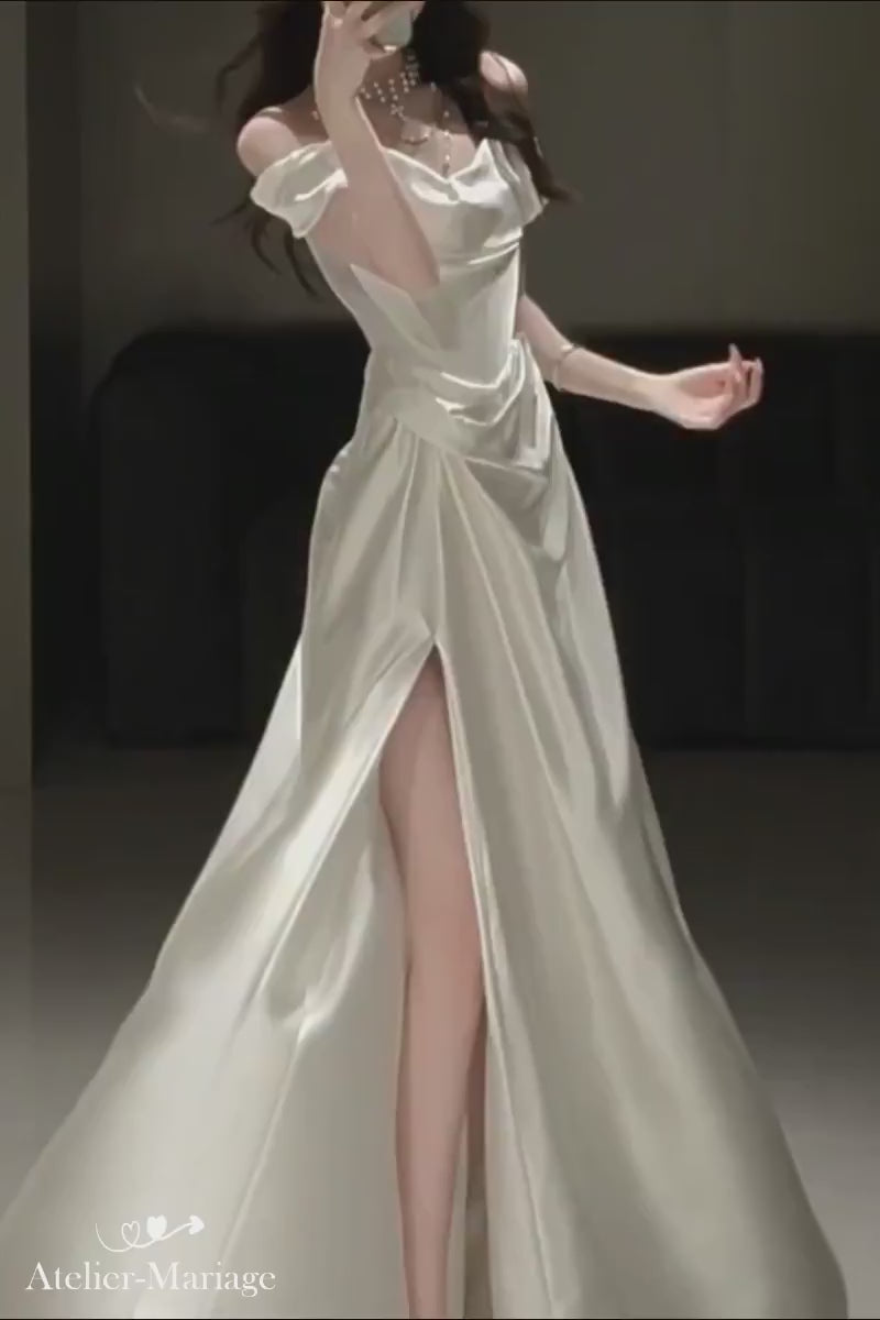 Mouvement fluide et tombé élégant du satin sur une robe de mariée col bardot avec fente glamour.