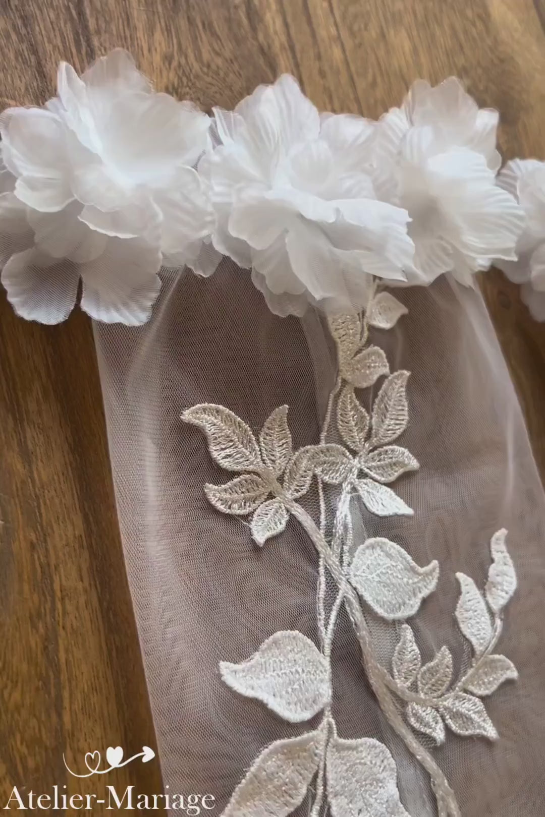 Vidéo zoom détaillé des manches amovibles mariage en dentelle florale — des fleurs satin 3D au poignet, posées sur plateau bois