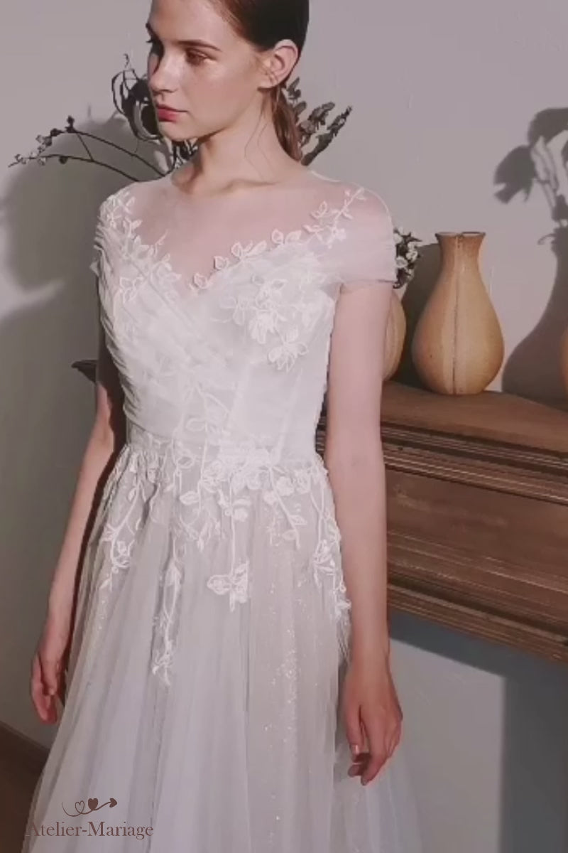 Gros plan en vidéo sur les délicats motifs floraux perlés et la coupe romantique d'une robe de mariée bohème avec col bateau.