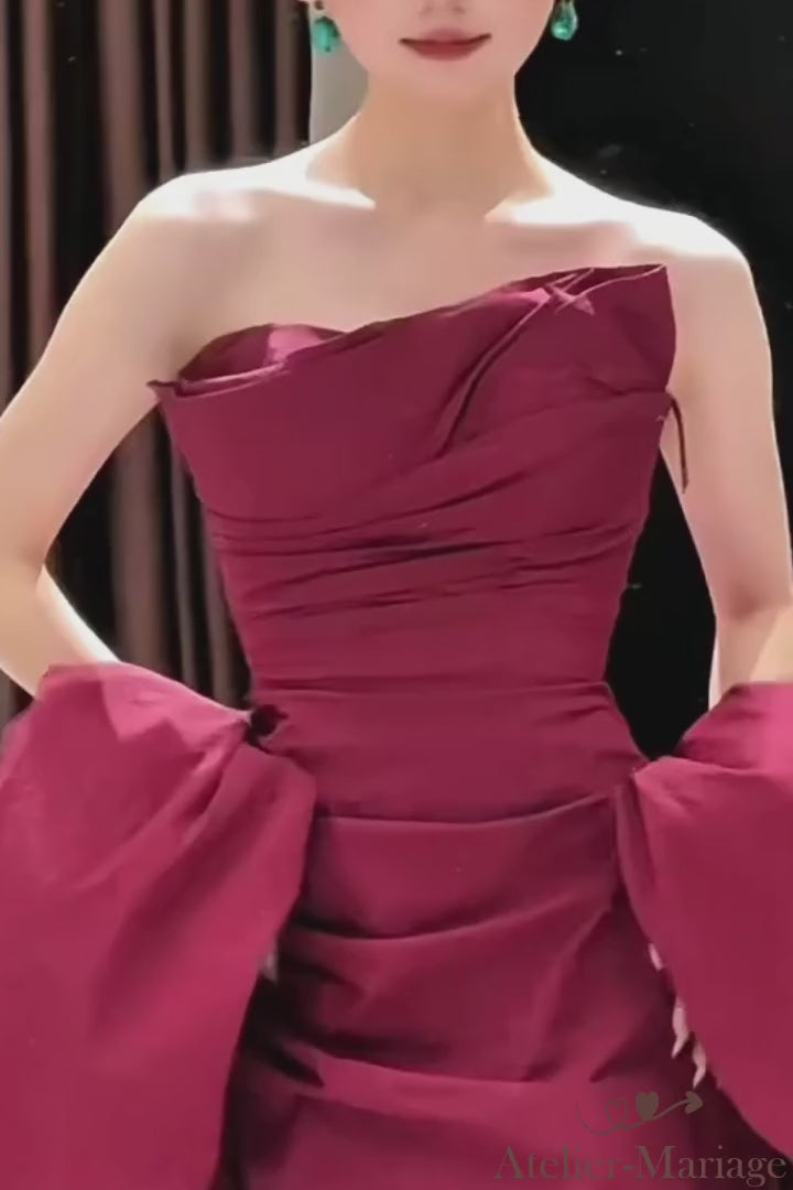 Gros plan sur le drapé artisanal et les finitions haute couture d'une robe de soirée bordeaux.