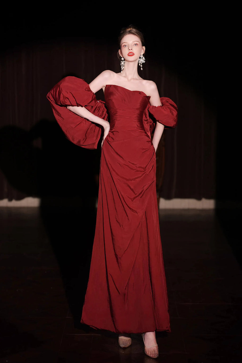 Femme élégante portant une robe de gala rouge bordeaux en taffetas avec des manches bouffantes spectaculaires.
