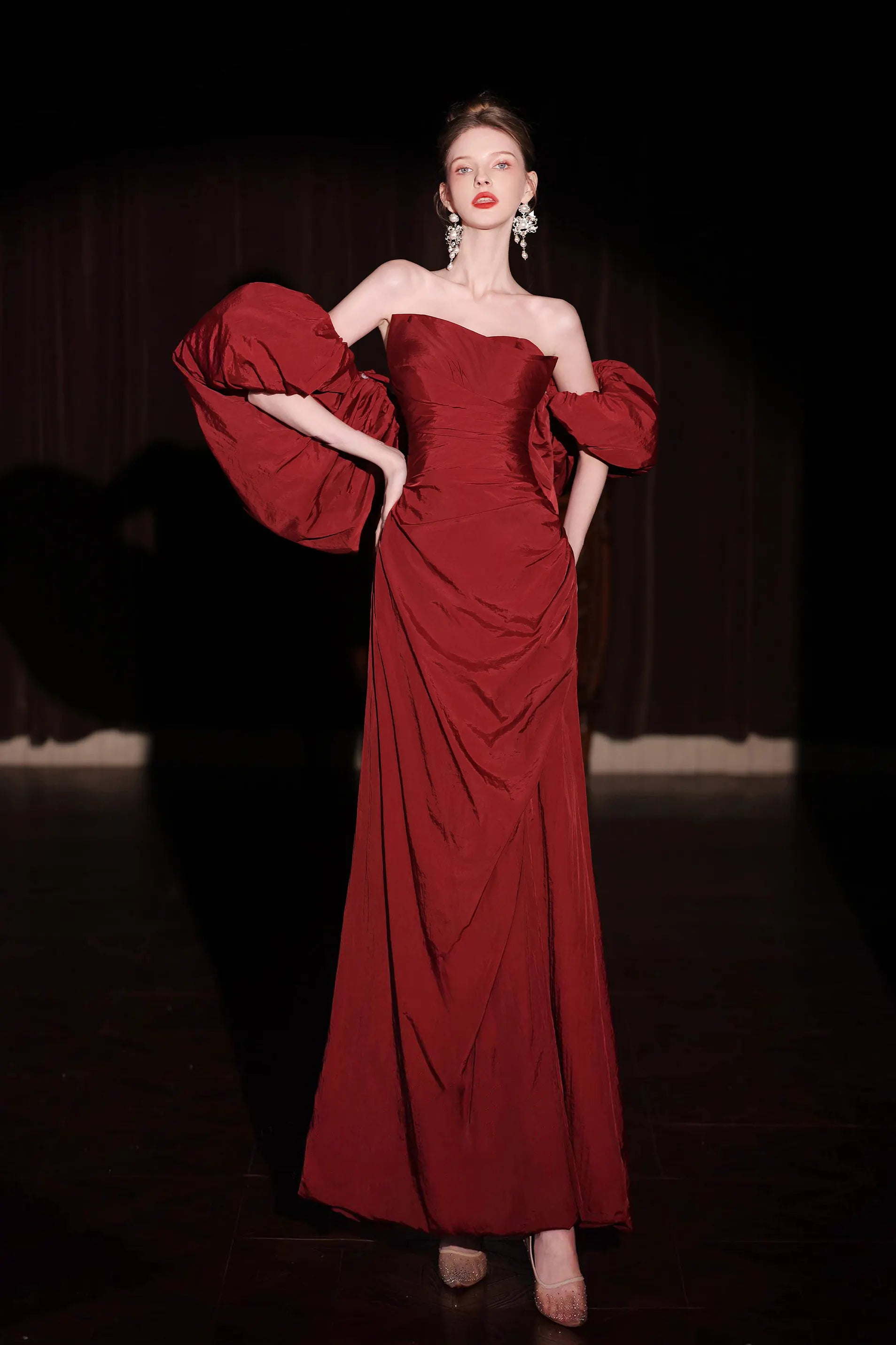 Femme élégante portant une robe de gala rouge bordeaux en taffetas avec des manches bouffantes spectaculaires.