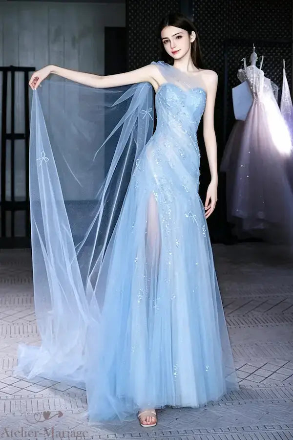 Vue de profil d'une robe de mariée bleu ciel avec épaule asymétrique et traîne légère en tulle pailleté, création Atelier Mariage.