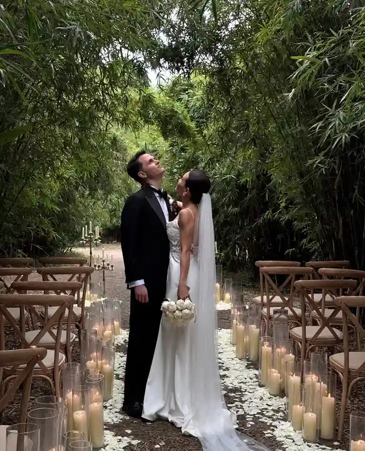 Mariés dans une allée de bambous, la mariée vêtue d'une robe de mariée fluide et champêtre au tombé vaporeux avec long voile