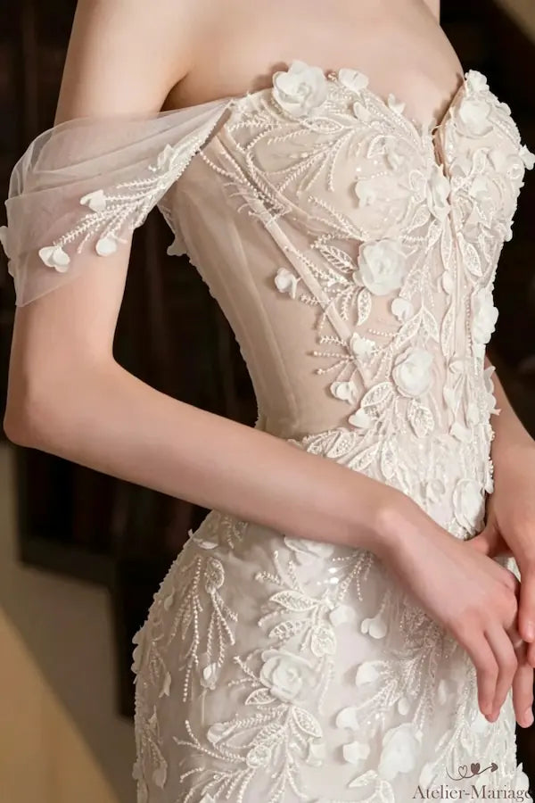 Autre gros plan sur le corsage de la robe de mariée, mettant en valeur les nuances crème du tulle et la texture riche des ornements floraux en relief. Qualité et raffinement assurés.