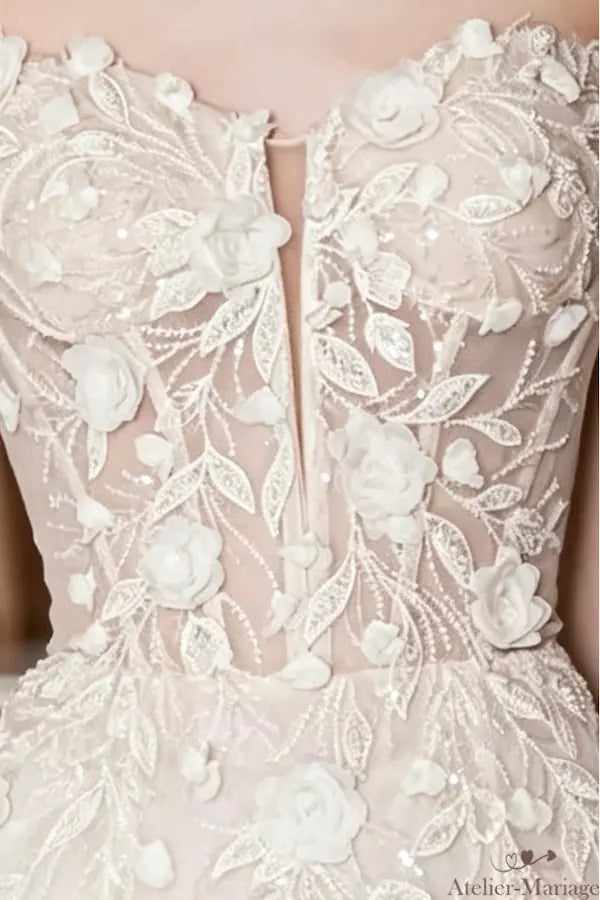 Gros plan détaillé du corsage d'une robe de mariée bohème : dentelle florale blanche exquise, broderies de perles et décolleté plongeant illusion. Voir les détails de nos finitions.