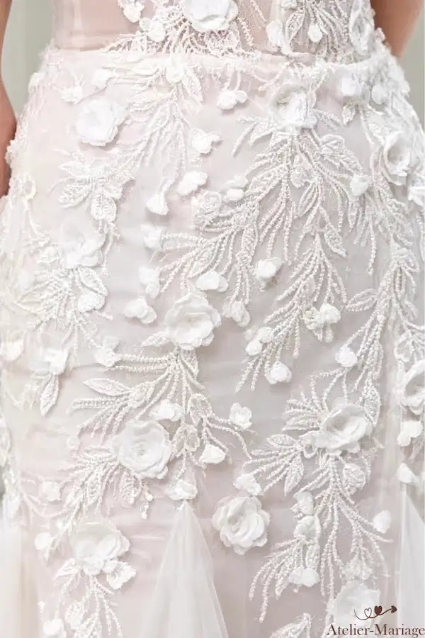 Vue rapprochée sur la hanche de la mariée, illustrant la transition parfaite entre le corsage en dentelle et la jupe en tulle, avec des détails floraux supplémentaires. Une pièce d'exception.