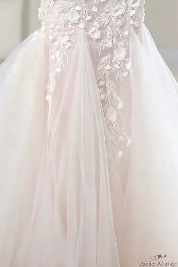 Partie inférieure de la robe de mariée bohème avec une jupe évasée en tulle fluide et une traîne légère, ornée d'applications florales éparses. Optez pour l'élégance et la fluidité.