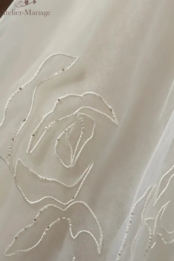 Vue rapprochée de les broderies florales délicates ornées de cristaux, soulignant la silhouette princesse.