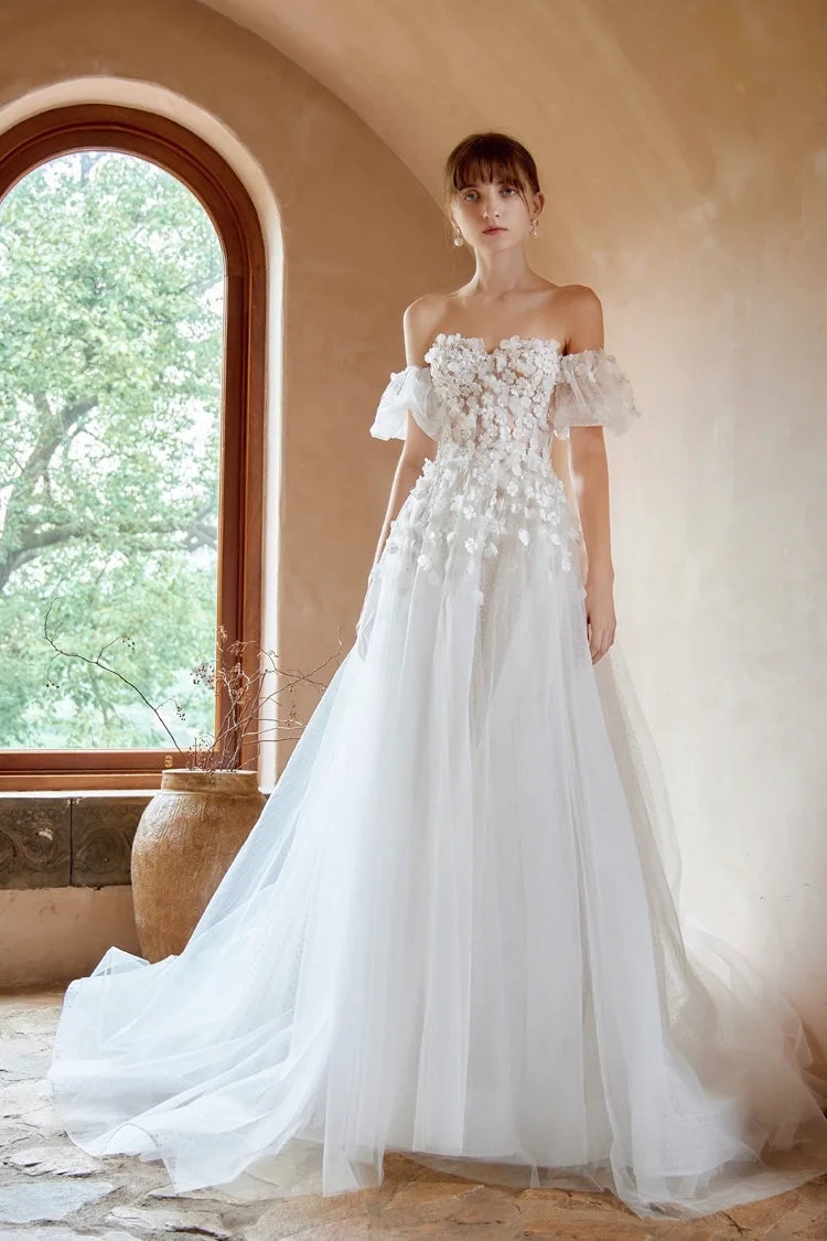 Robe de mariée romantique en tulle avec col Bardot et applications de fleurs 3D.