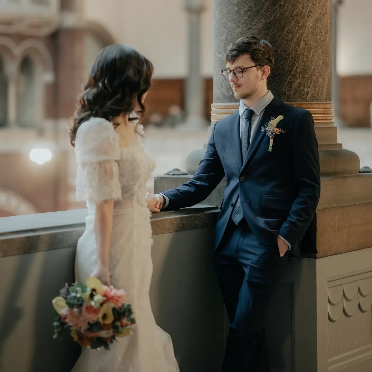 Couple de mariés complices en ville, la mariée porte une magnifique robe fluide sur-mesure idéale pour la mairie