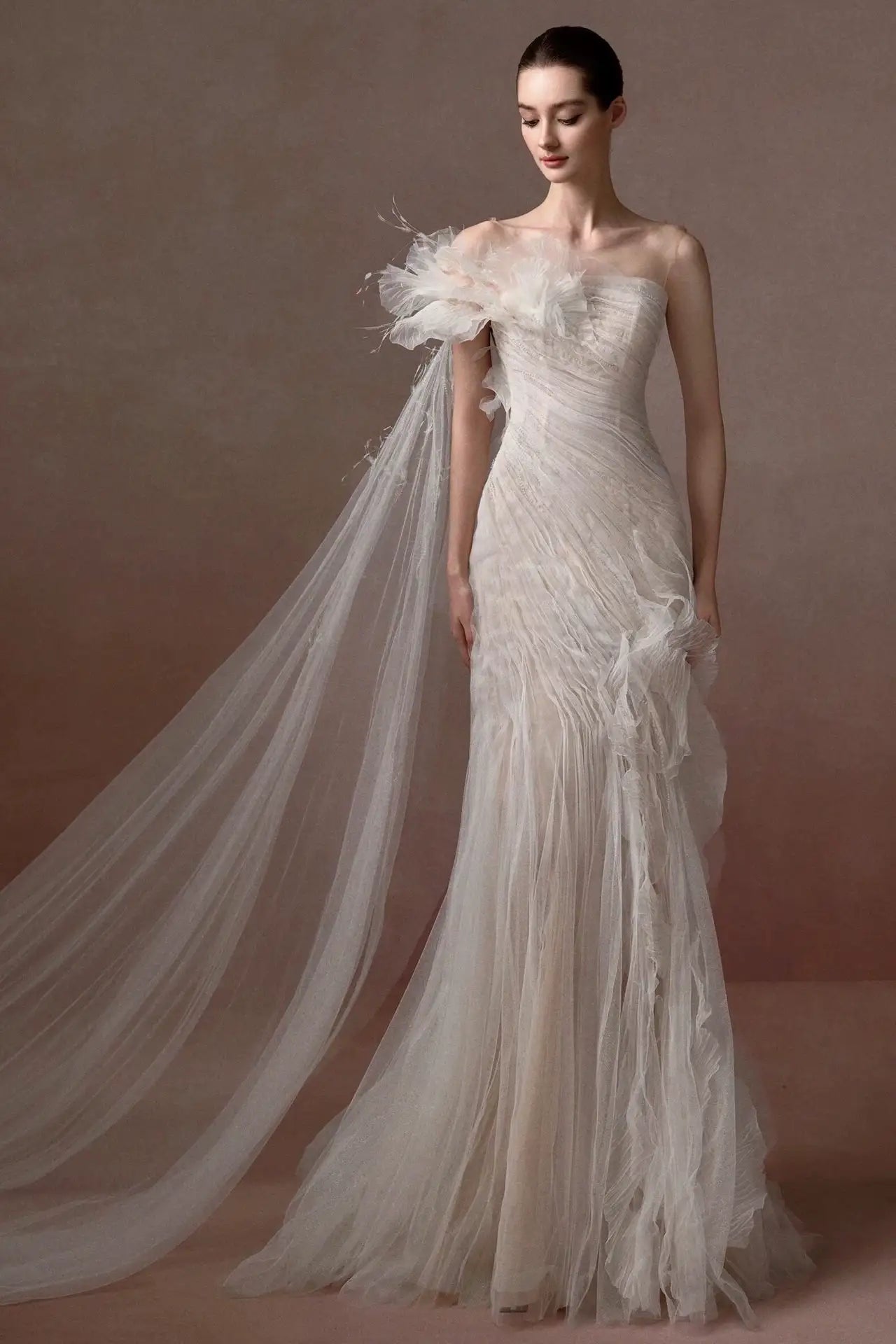 Design avant-gardiste d'une robe de mariée en tulle ornée de plumes et fleurs 3D.