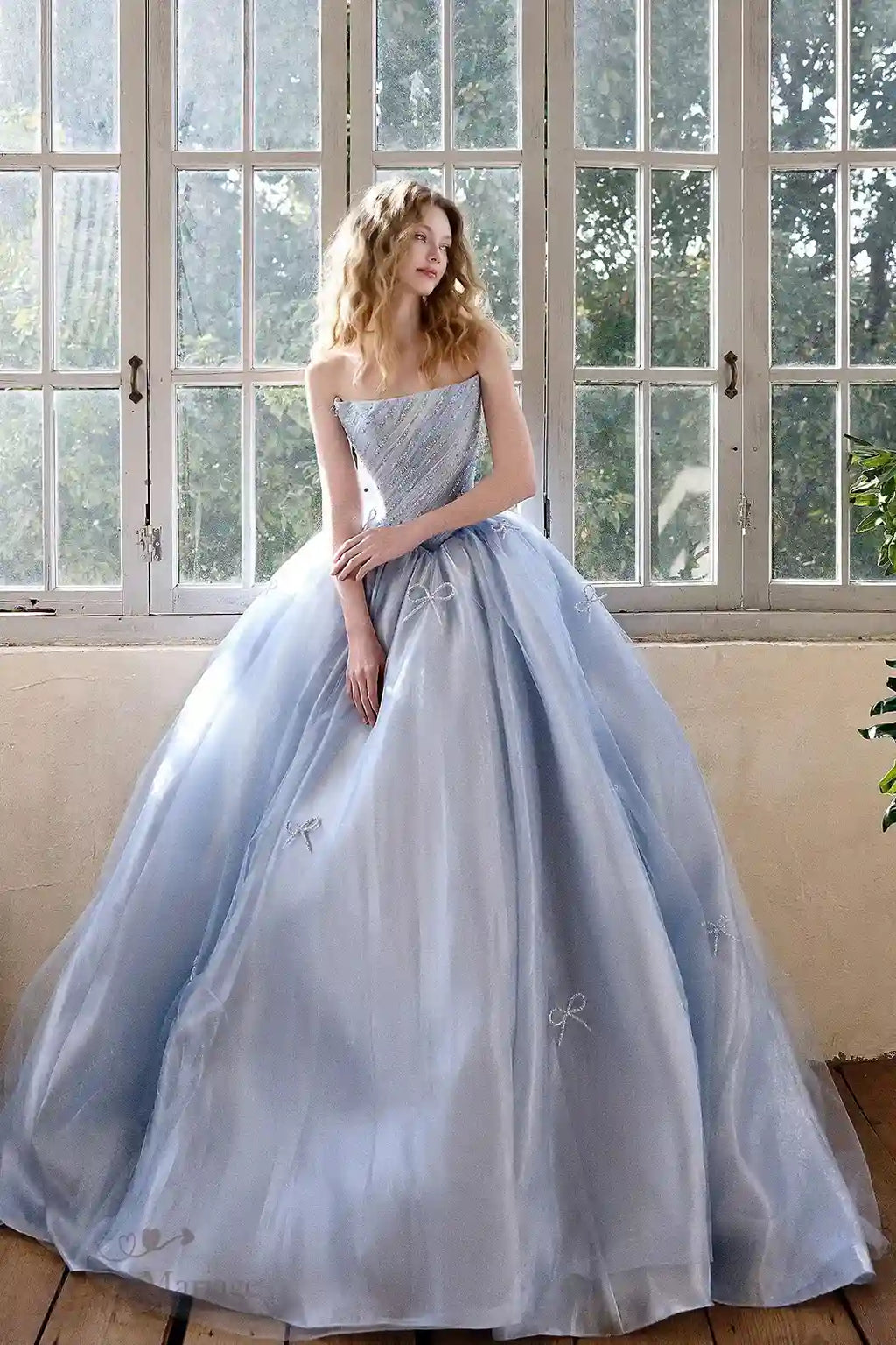 Robe de mariée coupe princesse de couleur bleu ciel féerique, ornée de petits nœuds 3D et de strass scintillants.