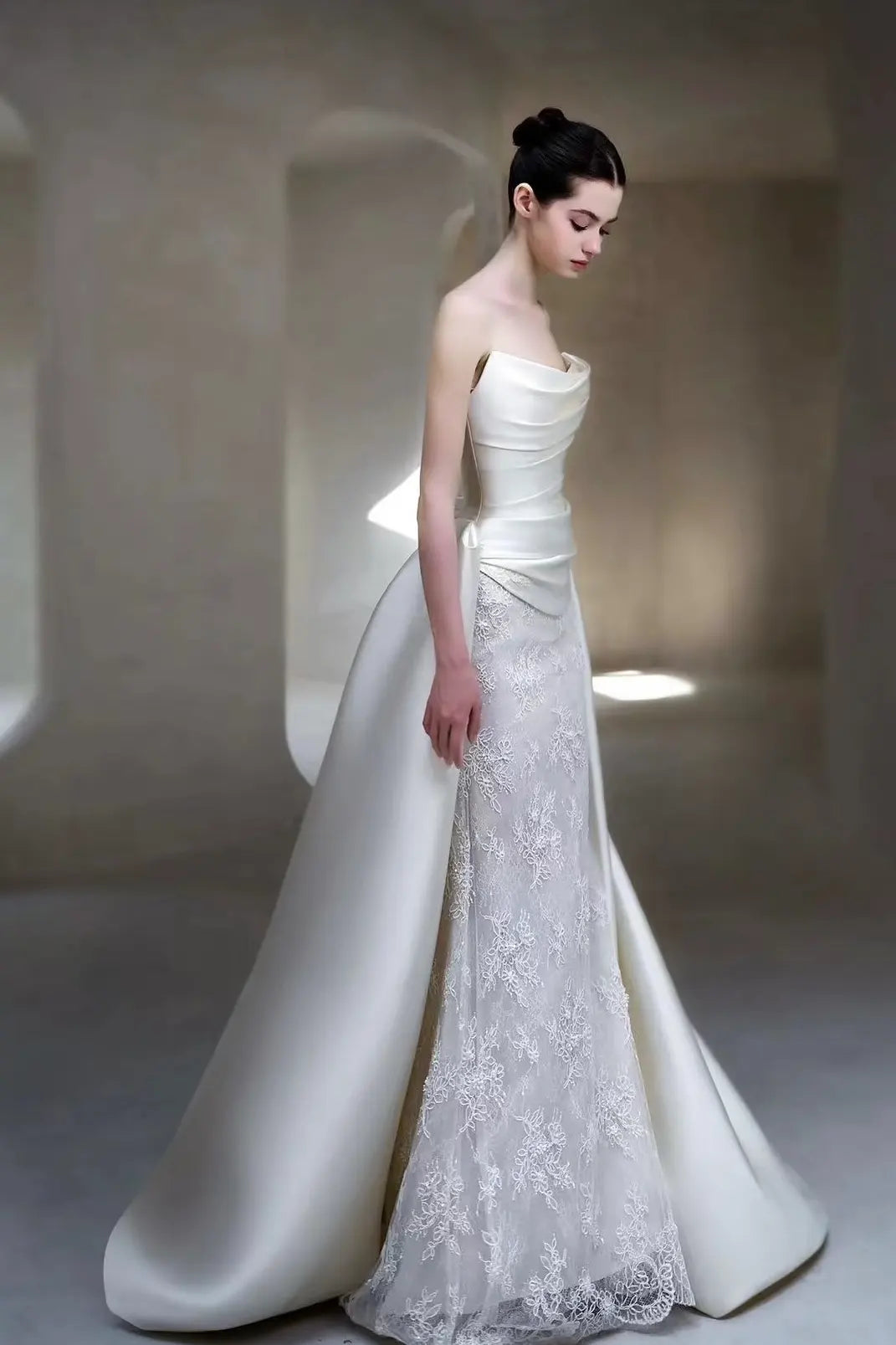 Profil élégant d'une robe de mariée sirène mettant en valeur la silhouette sculptée et la majestueuse traîne en satin.