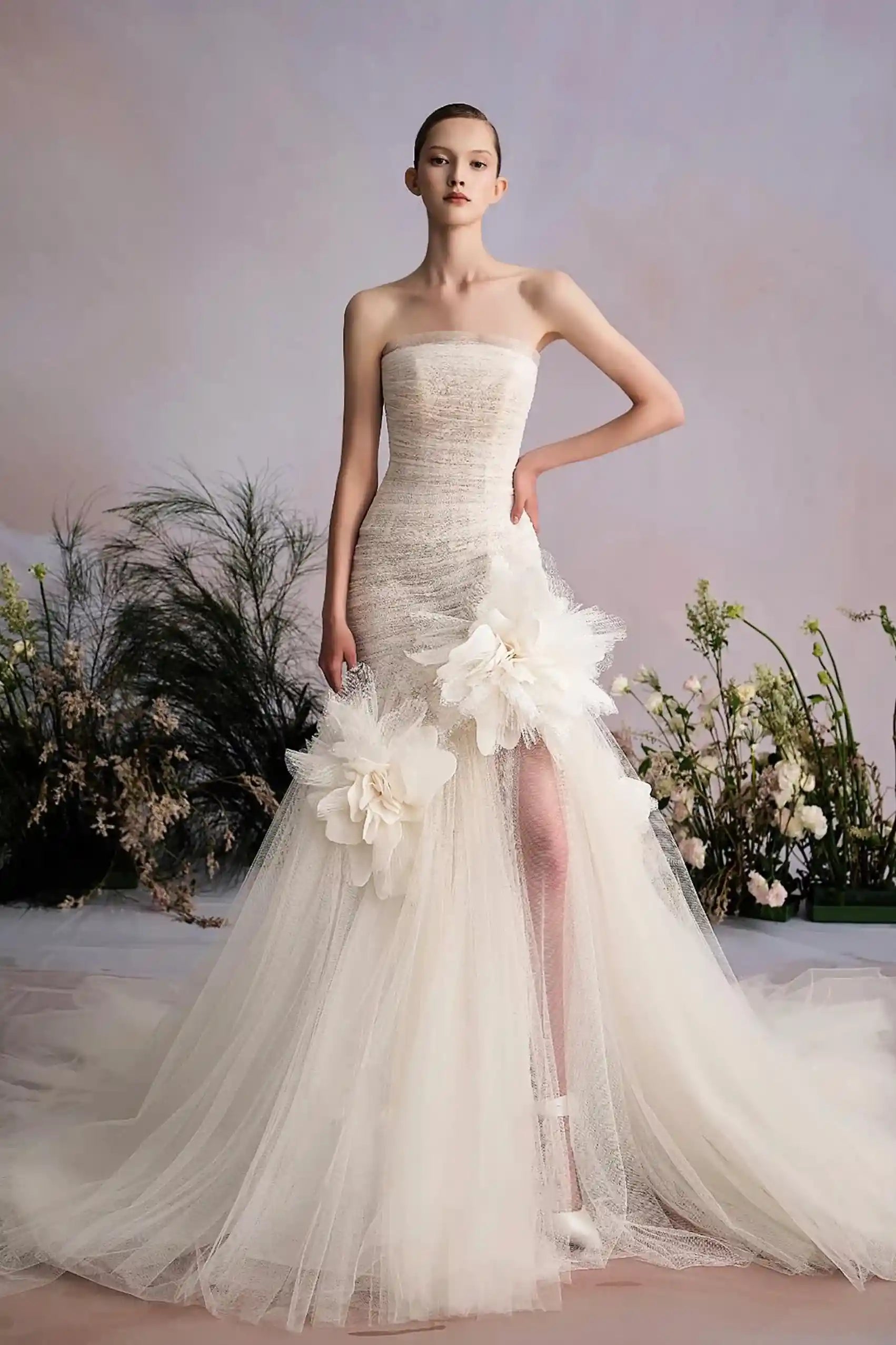 Robe de mariée longue et fluide avec fente audacieuse et bustier sans bretelles orné de fleurs 3D.