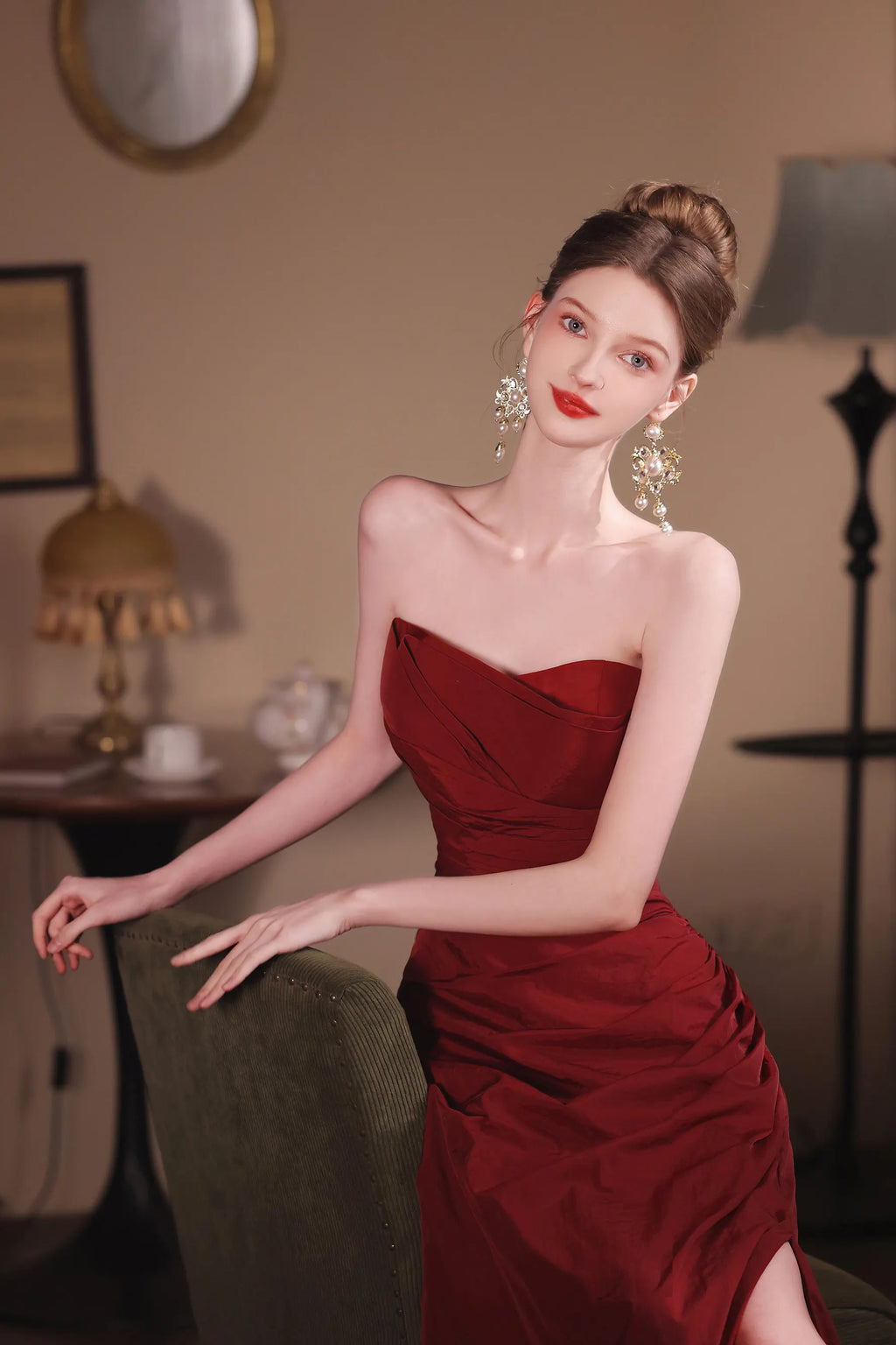 Modèle posant avec élégance dans une robe de soirée chic rouge bordeaux, mettant en valeur le corset ajusté et les épaules dénudées.