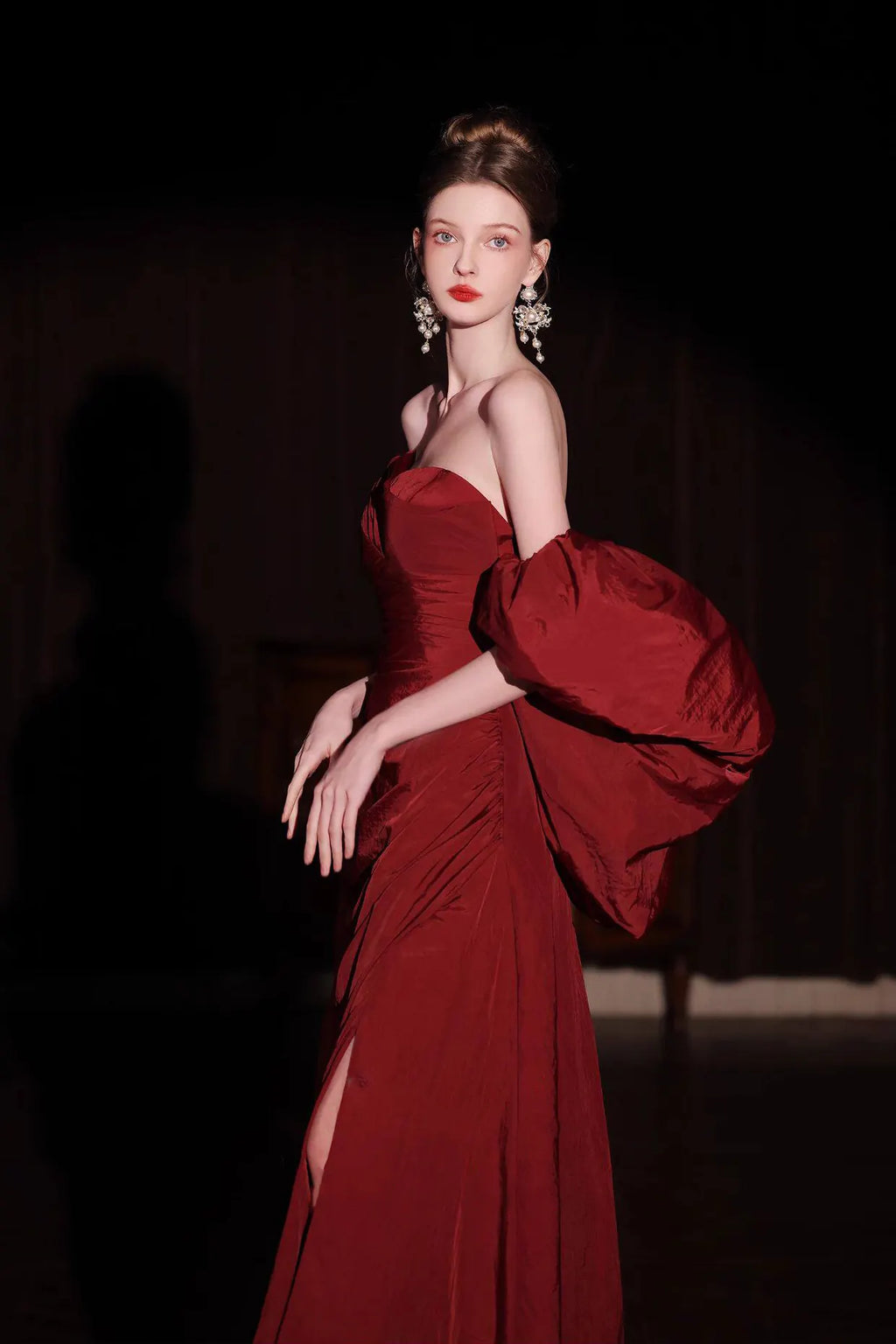 Femme élégante portant une robe de soirée rouge bordeaux en taffetas avec des manches bouffantes spectaculaires.