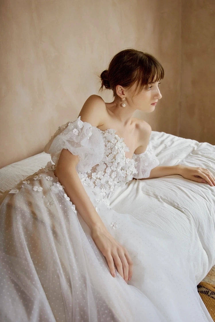 Mariée allongée portant une robe de mariée col Bardot romantique en tulle.