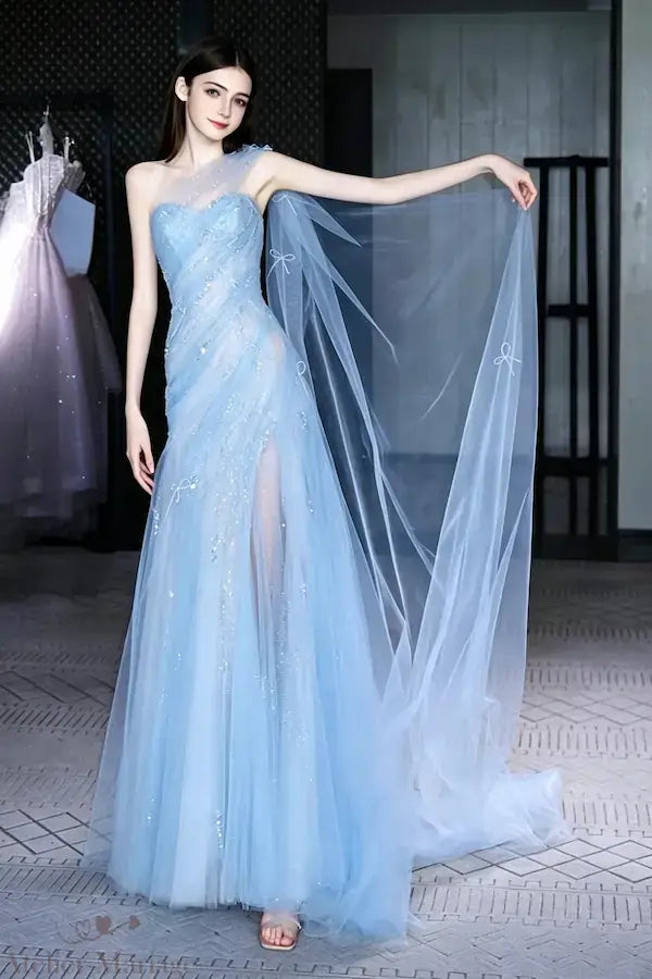 Mariée portant une robe bleu brume asymétrique avec une cape vaporeuse en tulle et une fente latérale élégante, style féerique.