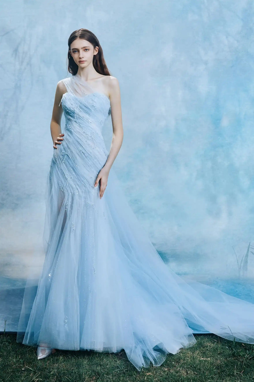 Mariée élégante portant une robe bleu brume en tulle avec décolleté asymétrique.