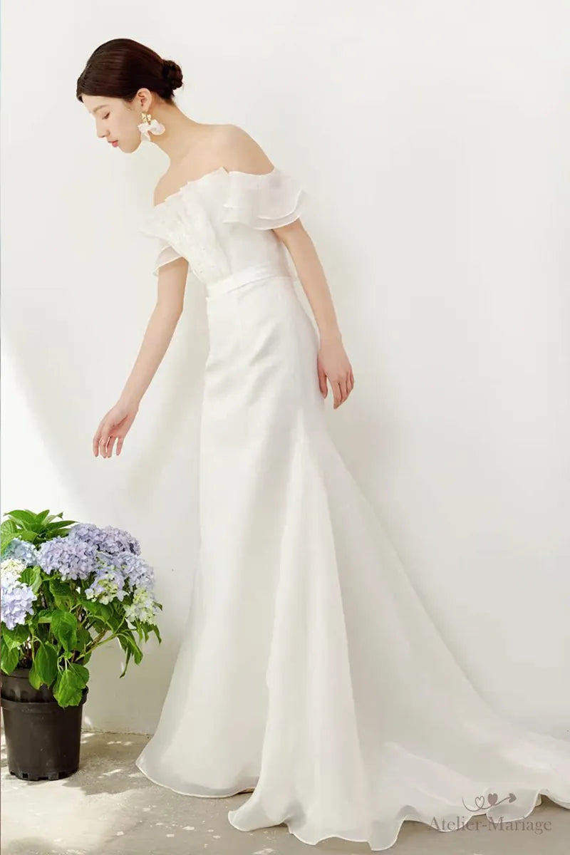 Femme en robe de mariée chic et simple bohème se penchant pour regarder les fleurs