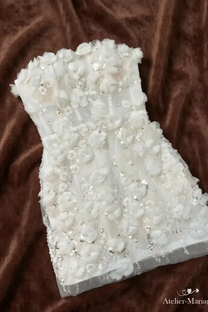 La robe courte Jardin de Lumière à plat, sans ses manches : bustier droit et jupe couverte de fleurs 3D