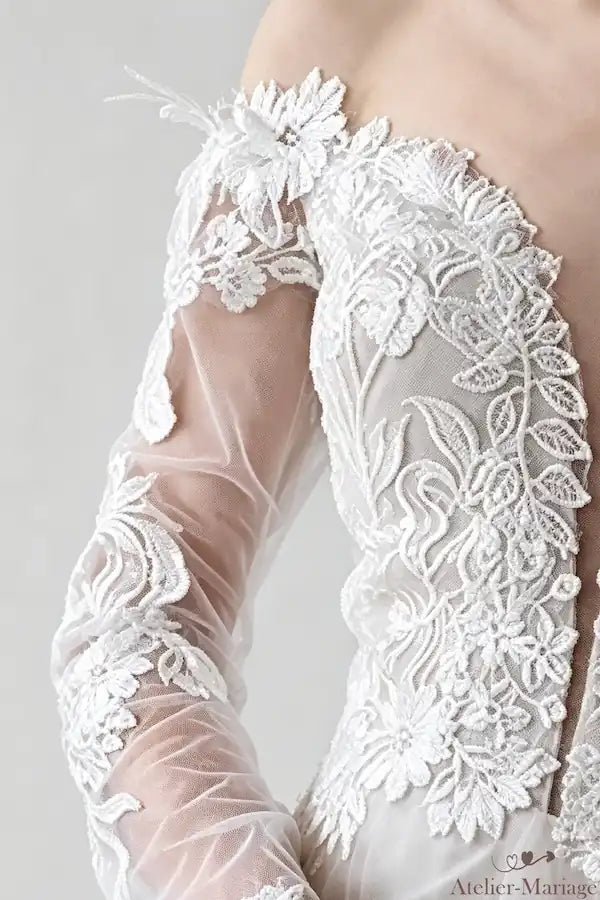 Détail de la dentelle en relief sur l'épaule et l'encolure de la robe de mariée