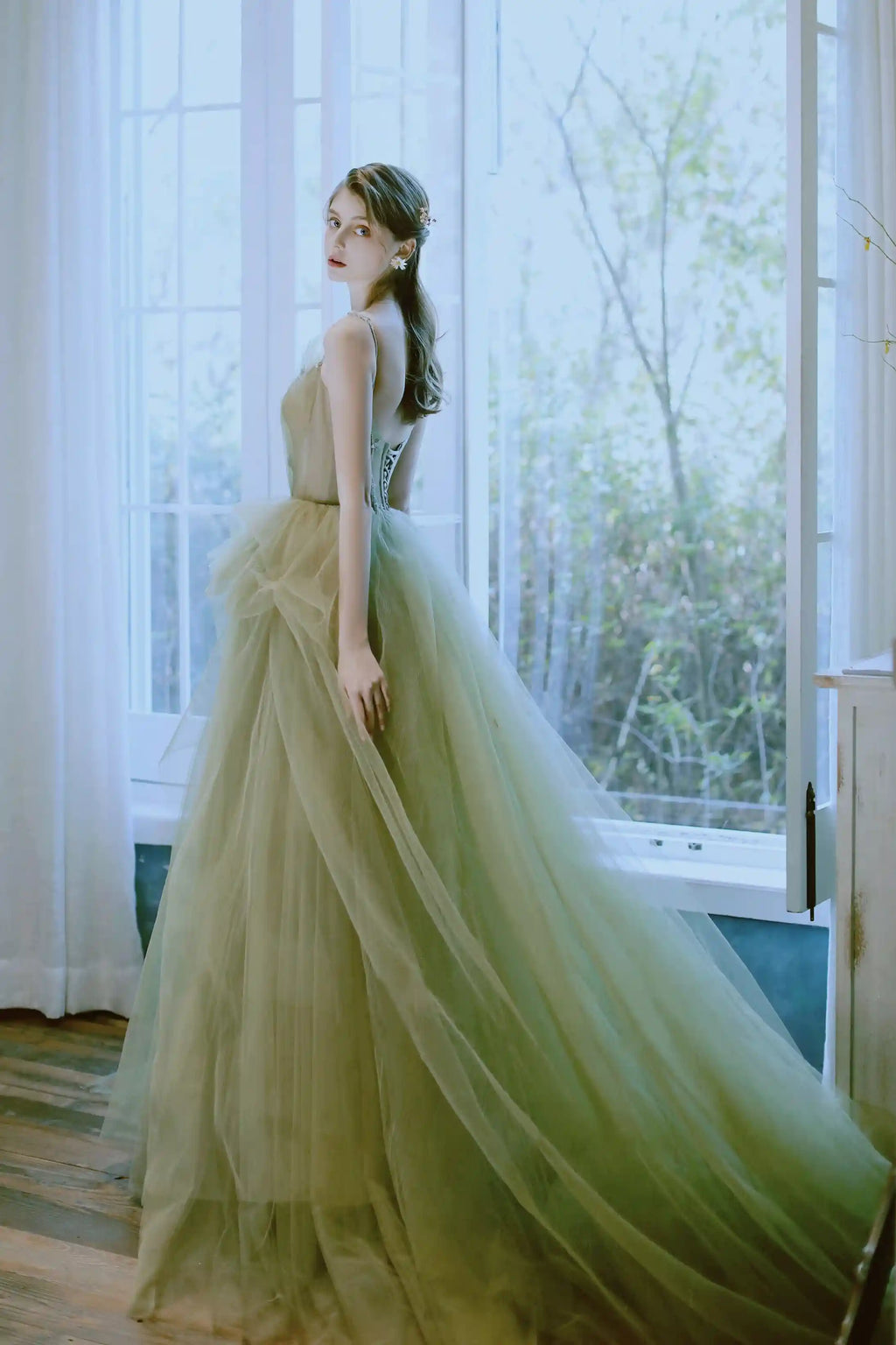 Vue de dos de la robe féerique montrant la longue traîne en tulle vert sauge fluide.