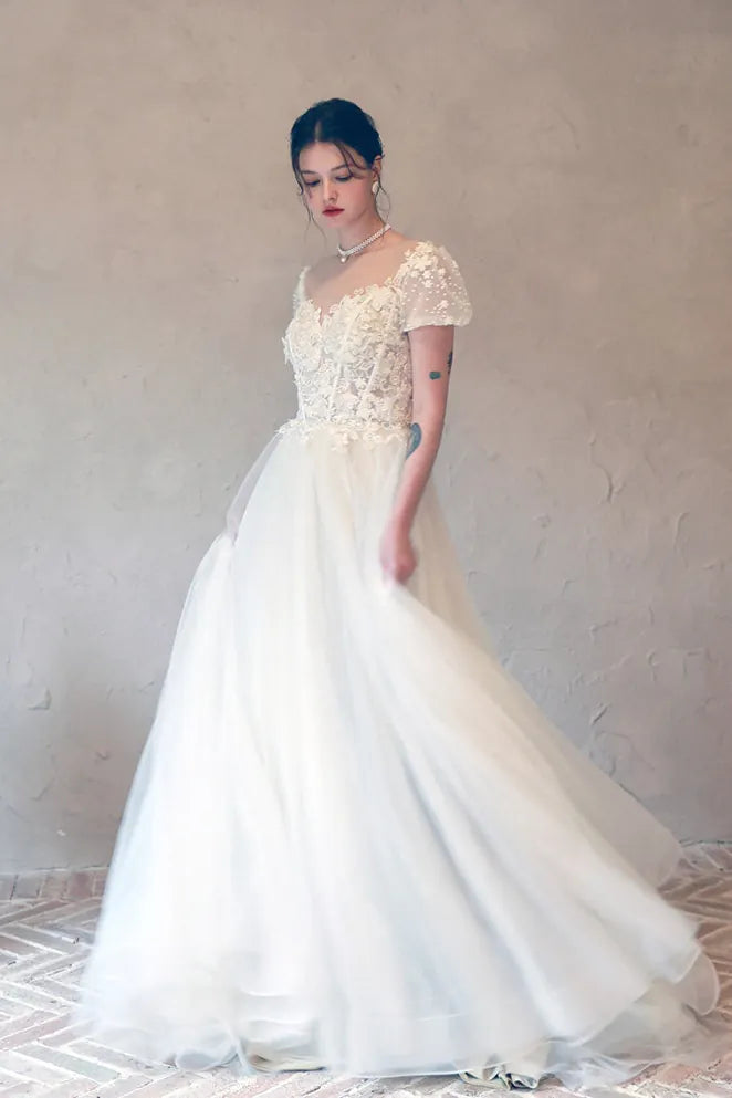 Robe de mariée silhouette princesse en tulle nude avec fleurs 3D brodées.