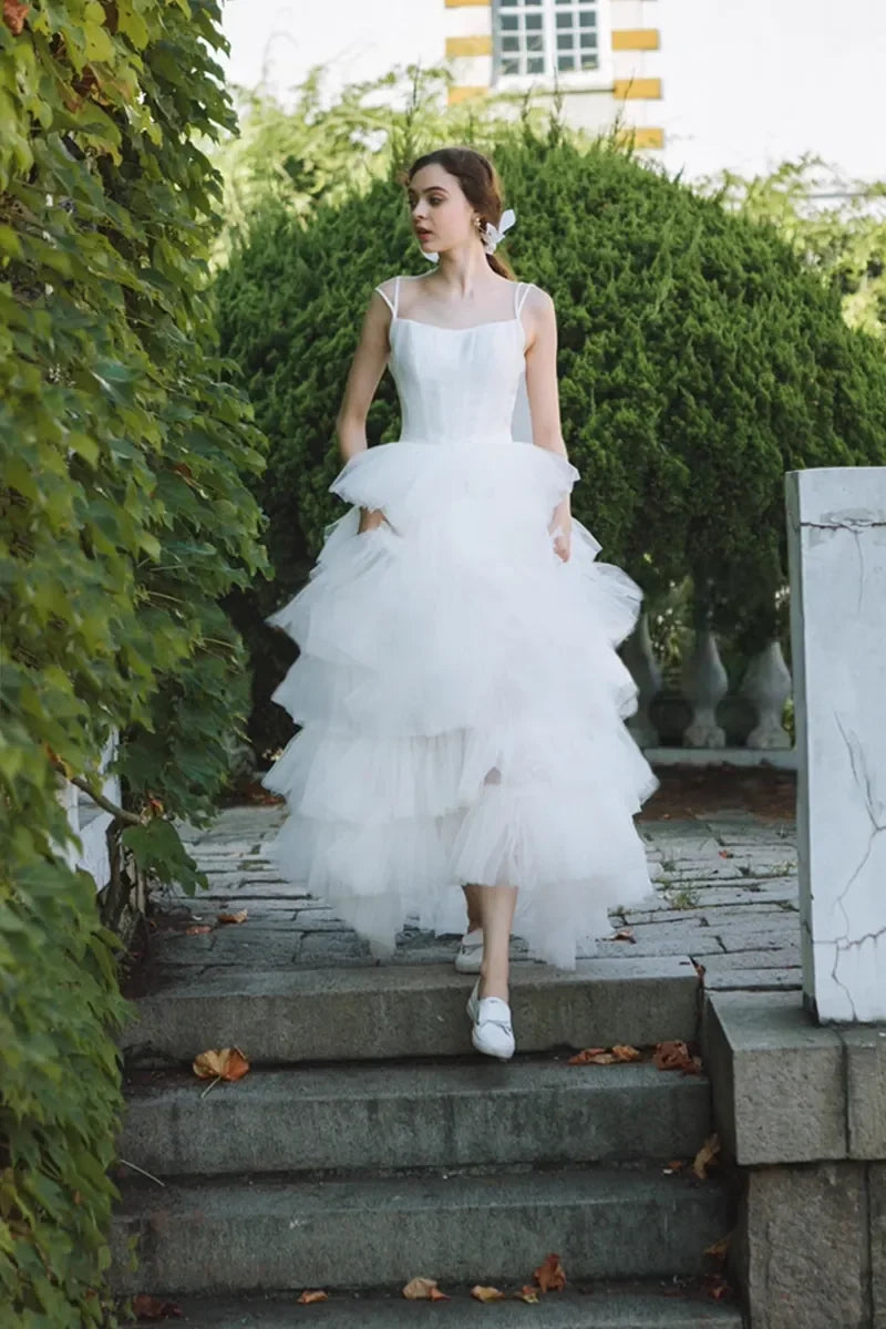Femme portant robe de mariée princesse en satin et tulle multicouches descendant l’escalier
