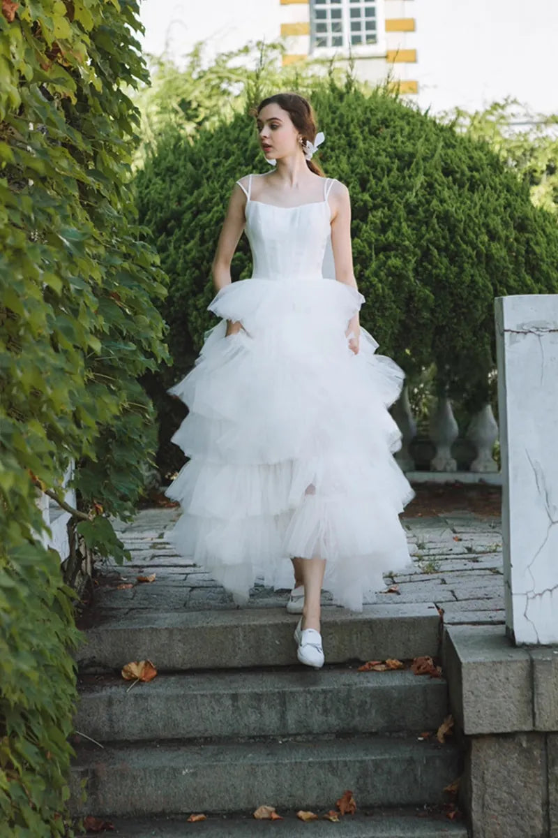 Femme portant robe de mariée princesse en satin et tulle multicouches descendant l’escalier