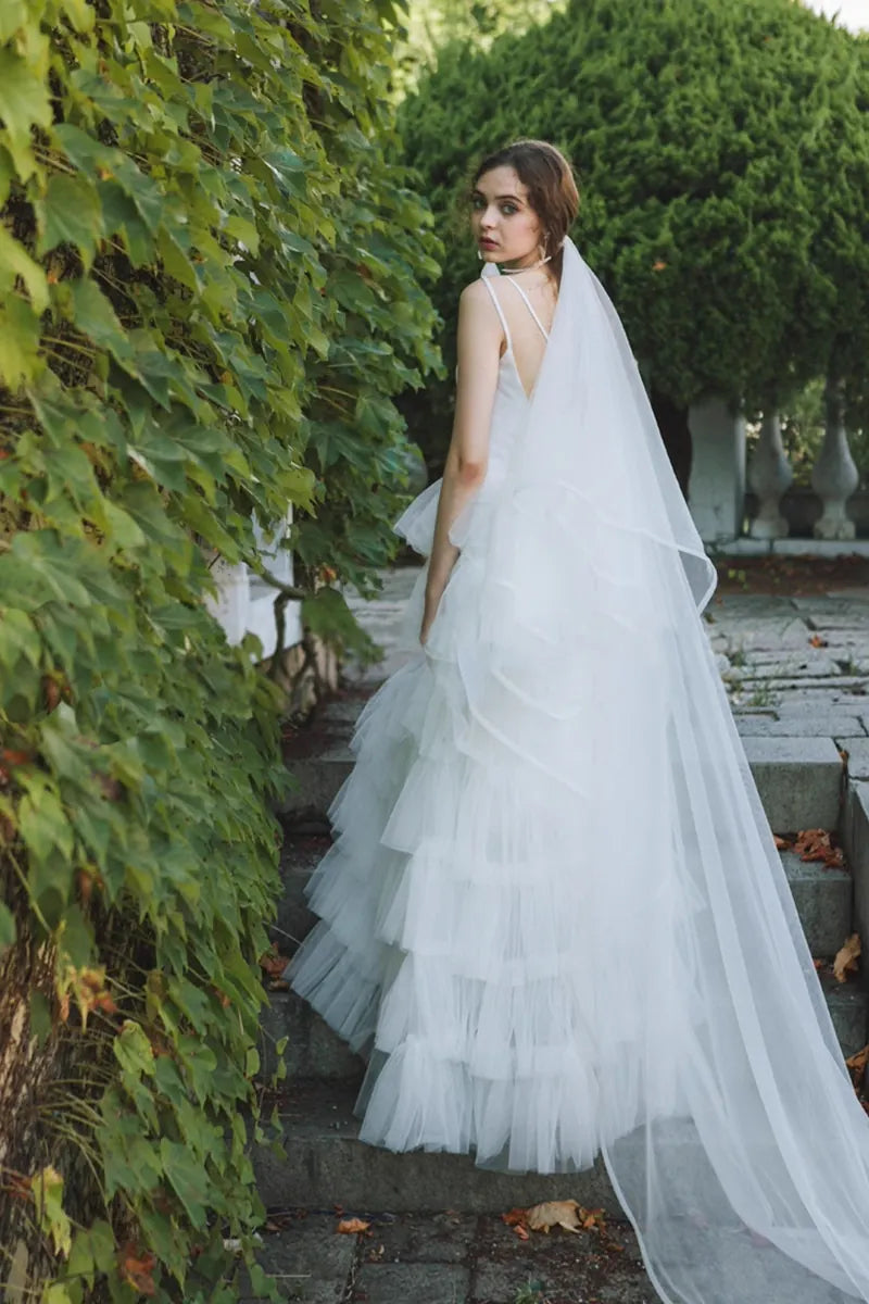 Femme portant robe de mariée princesse en satin et tulle multicouches, souriant en se retournant
