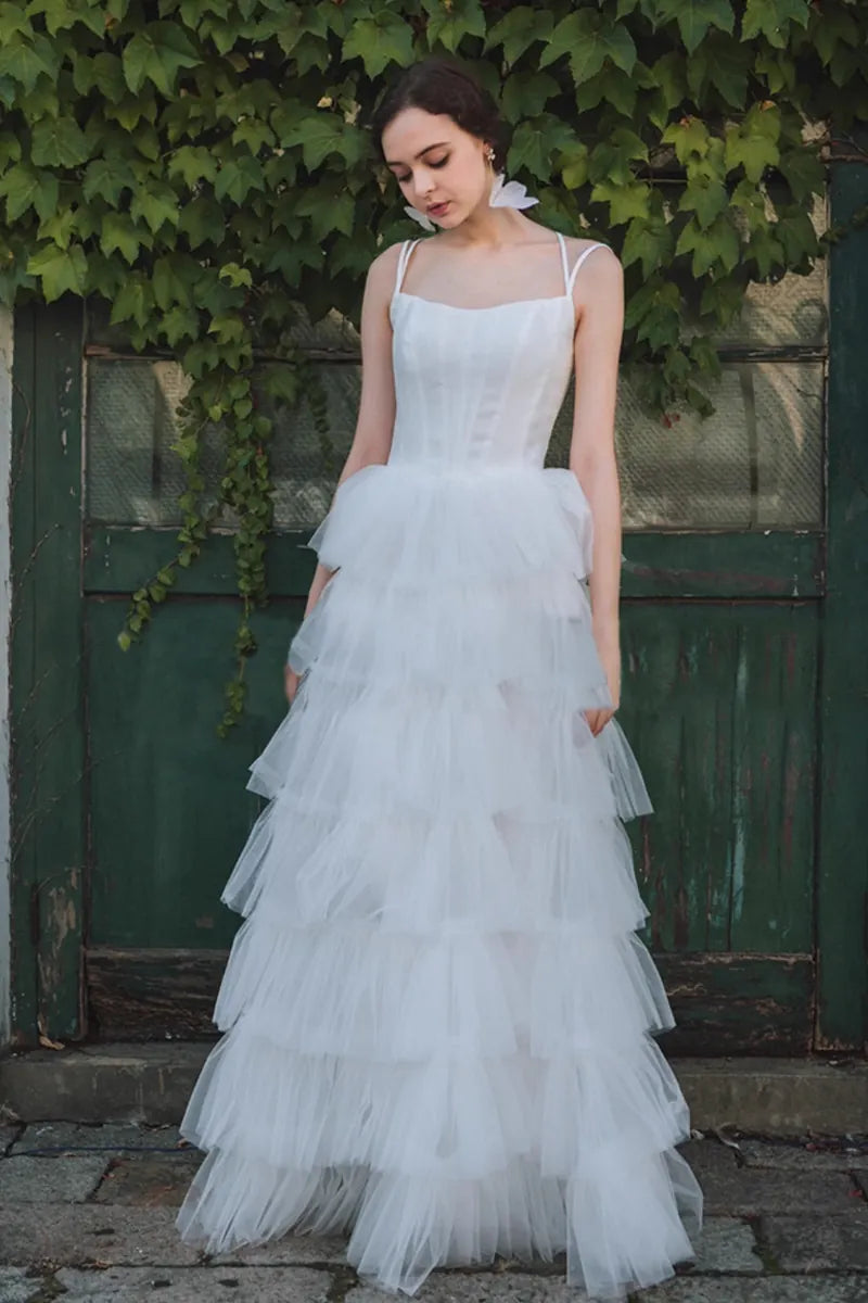Femme portant une robe de mariée princesse en satin et tulle multicouches, heureuse