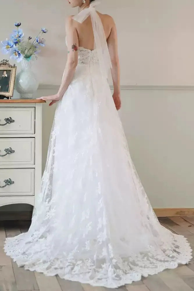 Détail attaches ruban délicat au cou pour robe de mariée dos nu sensuelle.